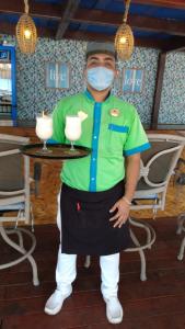 a man wearing a mask holding a table with two drinks at Hotel Club del Sol Acapulco by NG Hoteles in Acapulco