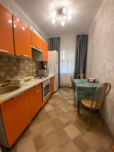 una cocina con armarios naranjas, una mesa, una mesa y un mantel en On Sevastopolskoy en Gelendzhik