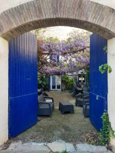 une porte bleue ouverte avec des chaises et un arbre avec des fleurs violettes dans l'établissement Gite les Glycines, à Llupia