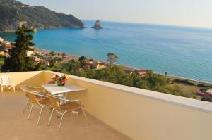 a balcony with a table and chairs and the ocean at Holiday Apartments Maria with pool and Panorama View - Agios Gordios Beach in Agios Gordios