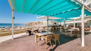 een terras met tafels en stoelen en het strand bij Hotel Sol e Mar Albufeira - Adults Only in Albufeira