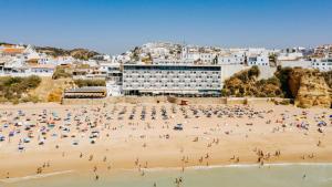 a group of people on a beach with buildings at Hotel Sol e Mar Albufeira - Adults Only in Albufeira
