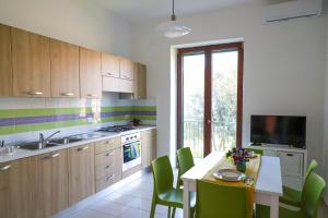 a kitchen with a table with green chairs and a television at Le Signore by Tizzano House in Procida