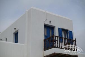 een wit gebouw met blauwe deuren en een balkon bij Comfy Room with Adorable View in Síkinos