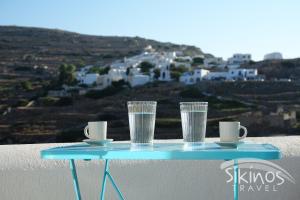 a blue table with cups and glasses on a ledge at Comfy Room with Adorable View in Sikinos