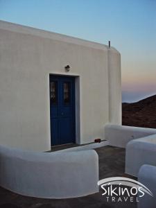 a white building with a blue door and white couches at Comfy Room with Adorable View in Síkinos