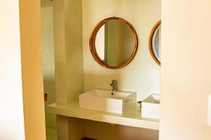 a bathroom with a white sink and a mirror at Tofinho Beach House in Praia do Tofo