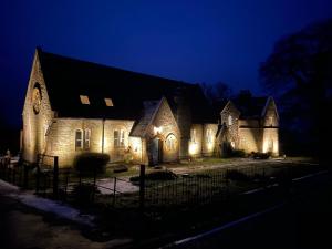 uma casa com luzes na frente à noite em The old school house em Burwarton