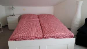 a bed with red pillows on it in a room at Apartment Gosch an der Skiwiese in Braunlage