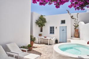 um pátio com uma banheira de hidromassagem e cadeiras e uma casa em 2 bedroom charming villa with outdoors jacuzzi em Megalochori