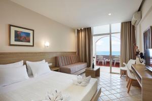 パノルモス・レティムノにあるEuropa Resort Hotelのベッドとソファ付きのホテルルーム