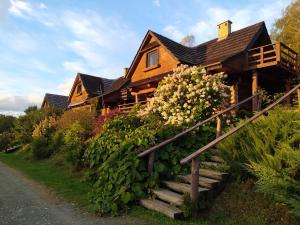 a wooden house with stairs leading up to it at Wilcza Jama - domki z bali in Lutowiska