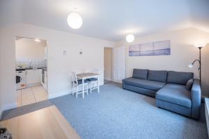 a living room with a blue couch and a kitchen at 2 Abbey Mews, Leiston in Leiston