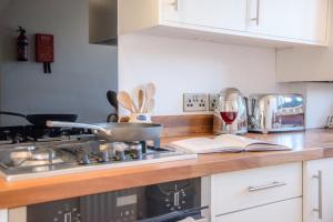 a kitchen counter with a stove and a glass of wine at 3 Oaks Court, Thorpeness in Thorpeness