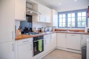 a kitchen with white cabinets and a stove top oven at 3 Oaks Court, Thorpeness in Thorpeness +10 photos