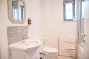 a white bathroom with a sink and a toilet at 3 Oaks Court, Thorpeness in Thorpeness