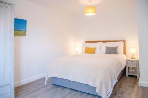 a bedroom with a large white bed with yellow pillows at 3 Oaks Court, Thorpeness in Thorpeness