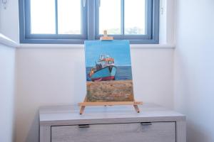 a painting of a boat on top of a dresser at 3 Oaks Court, Thorpeness in Thorpeness