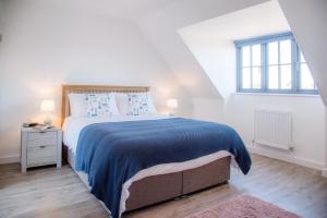 a white bedroom with a large bed and a window at 3 Oaks Court, Thorpeness in Thorpeness
