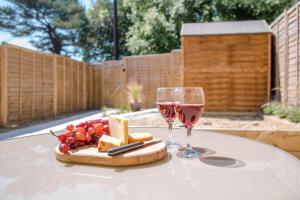 a table with two glasses of wine and a cheese board at 3 Oaks Court, Thorpeness in Thorpeness