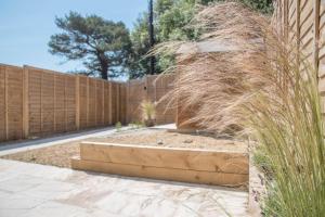 a garden with tall grass and a wooden fence at 3 Oaks Court, Thorpeness in Thorpeness