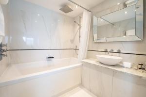 a white bathroom with a tub and a sink at Fistral Beach Hotel and Spa - Adults Only in Newquay