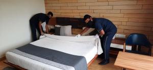 two men are making a bed in a room at Hotel Grand Elegance in Ahmedabad