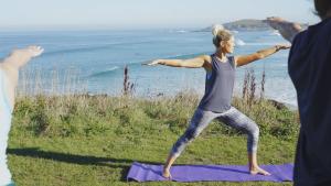 a woman doing yoga on a purple yoga mat near the ocean at Fistral Beach Hotel and Spa - Adults Only in Newquay