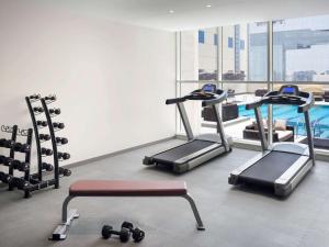 a gym with tread machines and a swimming pool at Adagio Aparthotel Jeddah Malik Road in Jeddah