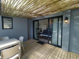 a room with a table and a balcony with a bed at Capricorn Studio One - 150m to Solar Beach, Patio & Braai, Wifi, DSTV & Netflix in Plettenberg Bay
