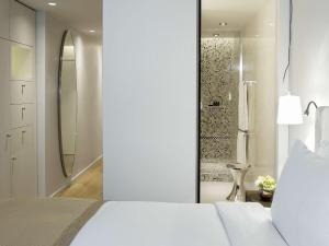 - une chambre avec un lit blanc et une douche dans l'établissement Sofitel Paris Arc De Triomphe, à Paris