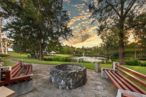 two benches and a fire pit in a park at Crowne Plaza Hawkesbury Valley, an IHG Hotel in Windsor