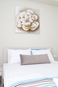 a white bed with a flower painting on the wall at Luxury Villa Siniori in Keramoti