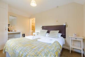 a bedroom with a large bed with a checked blanket at Volunteer Inn in Chipping Campden