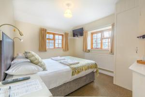 a bedroom with a bed and two windows at Volunteer Inn in Chipping Campden