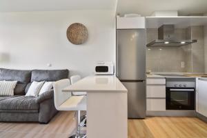 uma cozinha e sala de estar com um sofá e um frigorífico em Piso en la Isla em Isla de Arosa