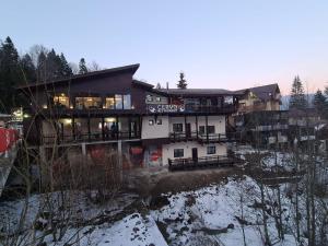 a building on a hill with snow on the ground at Ski Top Busteni in Buşteni
