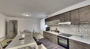a kitchen with wooden cabinets and a table with chairs at Pensiunea Magura Ocnei in Tîrgu Ocna