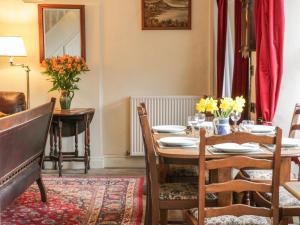 a dining room with a table and chairs and flowers at Bridgend Cottage in Skipton