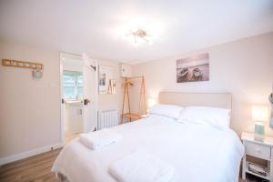 a bedroom with a large white bed with white pillows at Little House, Aldringham in Leiston