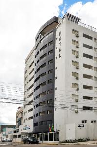 a large white building with cars parked in front of it at M Tower Hotel in Pelotas