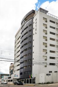 um grande edifício branco com carros estacionados em frente em M Tower Hotel em Pelotas