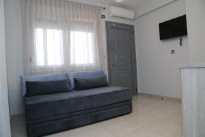 a couch in a living room with a television and a window at Luxury Villa Siniori in Keramoti