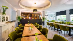 a restaurant with wooden tables and green chairs at Hotel Kryształ in Świeradów-Zdrój