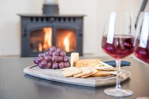 a plate of cheese and grapes and a glass of wine at Mill Cottage, Tunstall in Tunstall