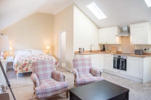 a kitchen and a bedroom with a bed and two chairs at Mill Cottage, Tunstall in Tunstall