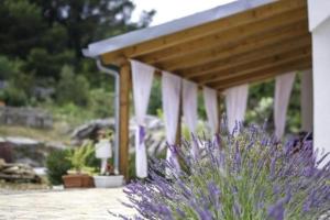 um pavilhão com cortinas brancas e um arbusto roxo em Holiday Home Lavanda em Raslina