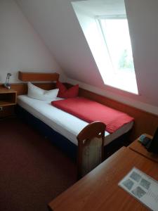 a bedroom with a bed with a red blanket and a window at Hotel & Restaurant Hildebrandt in Breitenrode