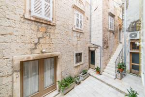 een steegje in een oud gebouw met een deur en planten bij Apartment Kalalarga in Makarska