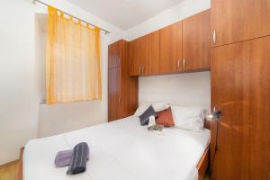 1 dormitorio con cama blanca y armarios de madera en Apartment Kalalarga en Makarska